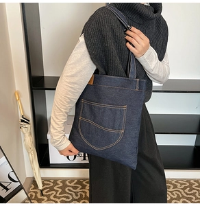 Detail of a large denim tote bag featuring contrast stitching and side leather label