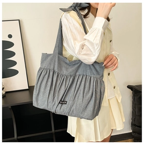 Detail of grey pleated fabric tote bag with bow strap and romance brand label