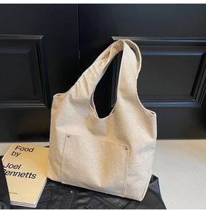 Close-up of cream corduroy tote bag featuring a front pocket with silver metal rivets