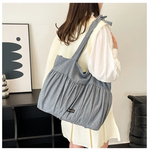 Detail of blue pleated tote bag with bow shoulder strap and Romance brand label