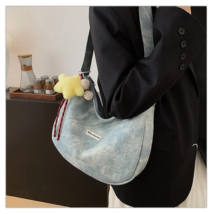 Close-up of blue denim hobo bag with star plush charm and woven rope detail