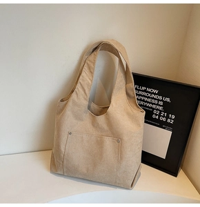Close-up of beige corduroy tote bag with front pocket and metal rivet details