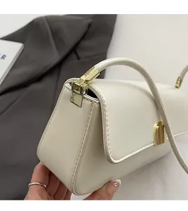 Close-up of cream leather shoulder bag side view with gold metal lock and leather strap