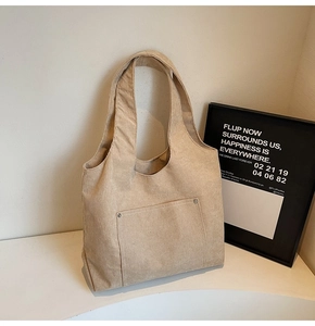 Detail of beige corduroy tote bag featuring striped texture and front pocket with rivet