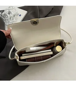 Top view showing the spacious interior of a white leather bag with phone and wallet
