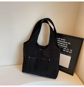 Close-up of black corduroy tote bag featuring contrast stitching and reinforced metal rivets