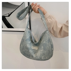 Detail of blue-grey denim moon bag featuring a JINYONGKANG leather brand patch