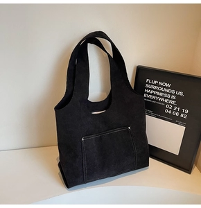 Detail of black corduroy tote bag showing contrast stitching and silver metal rivets