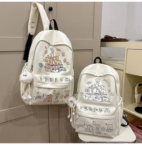 Detail view of white cartoon backpack with capybara prints and plush ball pendant