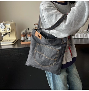 Macro view of denim tote bag with orange contrast stitching and leather logo detail