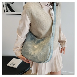 Detail showing the light blue washed denim texture and grid pattern on this shoulder bag