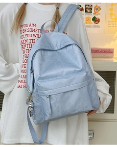 Detail of light blue nylon backpack featuring leaf pattern texture and astronaut charm