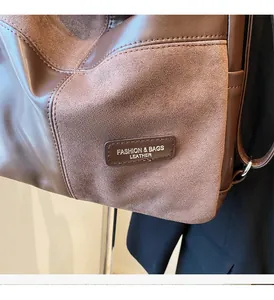 Detail of brown leather and suede patchwork bag with fashion leather embossed tag