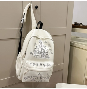 Close-up of beige cartoon backpack with cute bear illustrations hanging on a wooden door