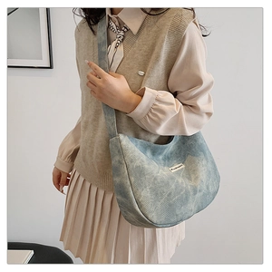 Detail of light blue quilted denim dumpling bag with wide strap on minimalist model