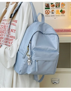 Detail of light blue floral nylon backpack with silver bear charm and metal zipper