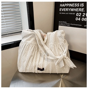 Detail of white polka dot tote bag with ruffles and a decorative bow on metal table
