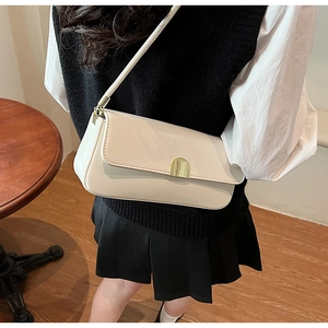Close-up of the elegant golden metal buckle on the cream white leather underarm bag