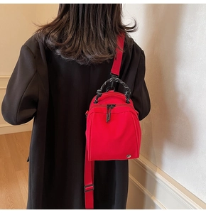 Rode nylon schelp tas gedragen op zwarte jas met geweven handgrepen en schouderriem