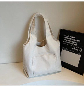 Detail of cream corduroy tote bag featuring front pocket with silver rivet accents
