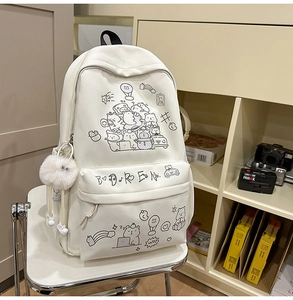 Detailed view of cream canvas backpack with cute cartoon prints and plush ball charm