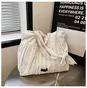 Close-up of white polka dot canvas tote bag featuring ruffled edges and Romane logo