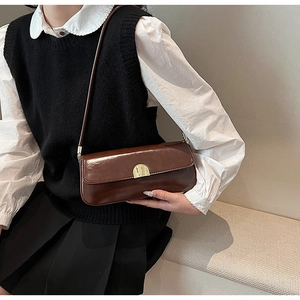 Close-up of a chocolate brown leather underarm bag with a gold semi-circle metal buckle