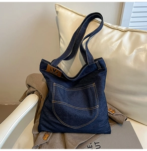 Close-up of denim tote bag featuring large front pocket and orange contrast stitching