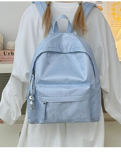 Detail of light blue backpack with leaf patterns, silver bear charm and Hoog embroidery