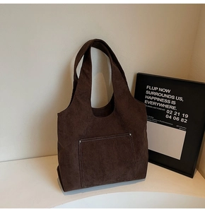 Detailed texture of brown corduroy tote bag with metal rivets and outer pocket