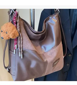 Detail of dark brown vintage velvet shoulder bag with teddy bear charm and fringe