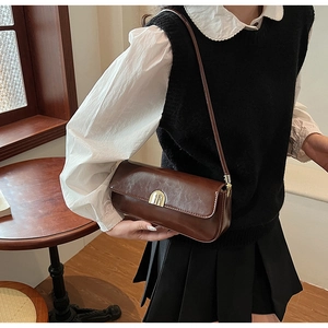 Macro detail of dark brown baguette bag with glossy texture and gold metal buckle