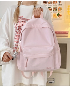 Light pink nylon backpack featuring an adjustable strap and cute silver bear charm detail