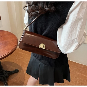 Detail of vintage brown leather underarm bag with gold buckle on shoulder