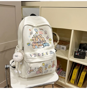 Detailed view of white cartoon capybara backpack featuring cute plush pompom and art print