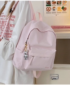 Side view of a light pink casual backpack featuring a cute silver bear charm decoration