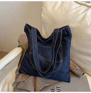 Detailed close-up of dark denim tote bag featuring yellow contrast stitching and soft texture
