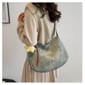 Detail of light blue denim hobo bag with yellow star plush charm and rope decor