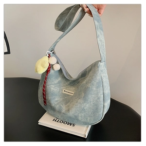 Close-up of light blue hobo bag showing woven texture and yellow plush pendant
