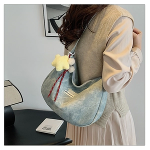 Detail of light blue denim hobo bag with star charm and JINYONGKANG logo on side