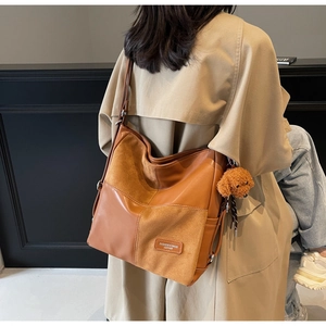 Close-up of caramel tote bag with leather patchwork detail and a teddy bear charm