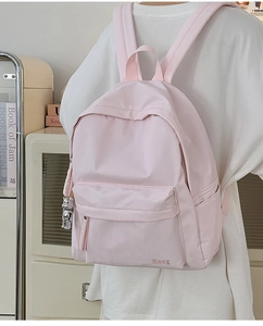Detail of light pink nylon backpack with Hoog embroidery and silver bear keychain charm