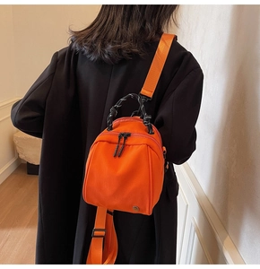 Detailed back view of a vibrant orange nylon backpack worn on a casual outfit