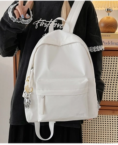 Detailed shot of white nylon backpack with Hoog logo and silver bear keychain