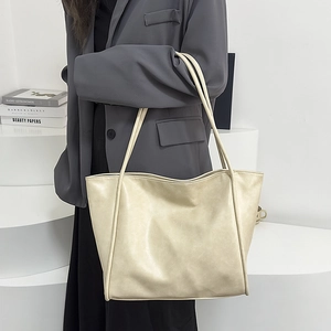 Vista detallada de bolsa tote de cuero PU crema con asas finas llevada por modelo