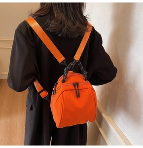 Mini oranje nylon rugzak van achteren getoond op een model met een zwarte blazer