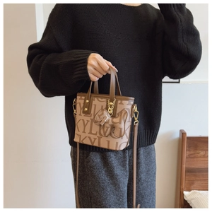 Detailansicht der Mini-Eimertasche mit Buchstabenmuster und Leder-Hundeanhänger