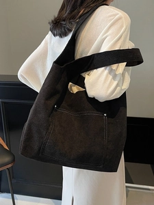 Fashionable black corduroy tote bag with large front pocket and white stitching detail