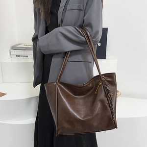 Detalle del bolso tote vintage de ecocuero marrón con colgante dorado y cuerda trenzada