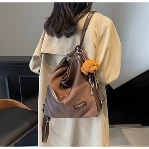Macro detail of brown patchwork tote bag with faux fur bear pendant and leather tag
